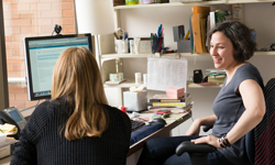 A student and a librarian talk in an office in the librar